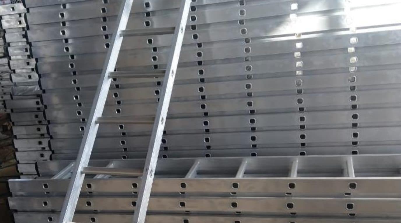 Stacked aluminium formwork panels and profiles in the GH Scaffolds warehouse, with an aluminium ladder resting against them.
