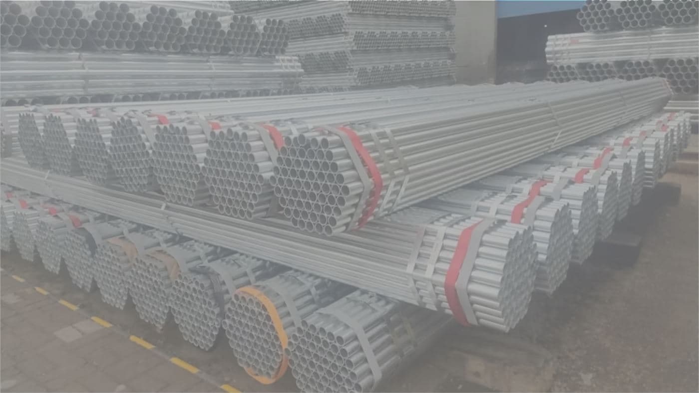 Bundles of galvanised steel tubes strapped together and stacked on pallets in a warehouse.